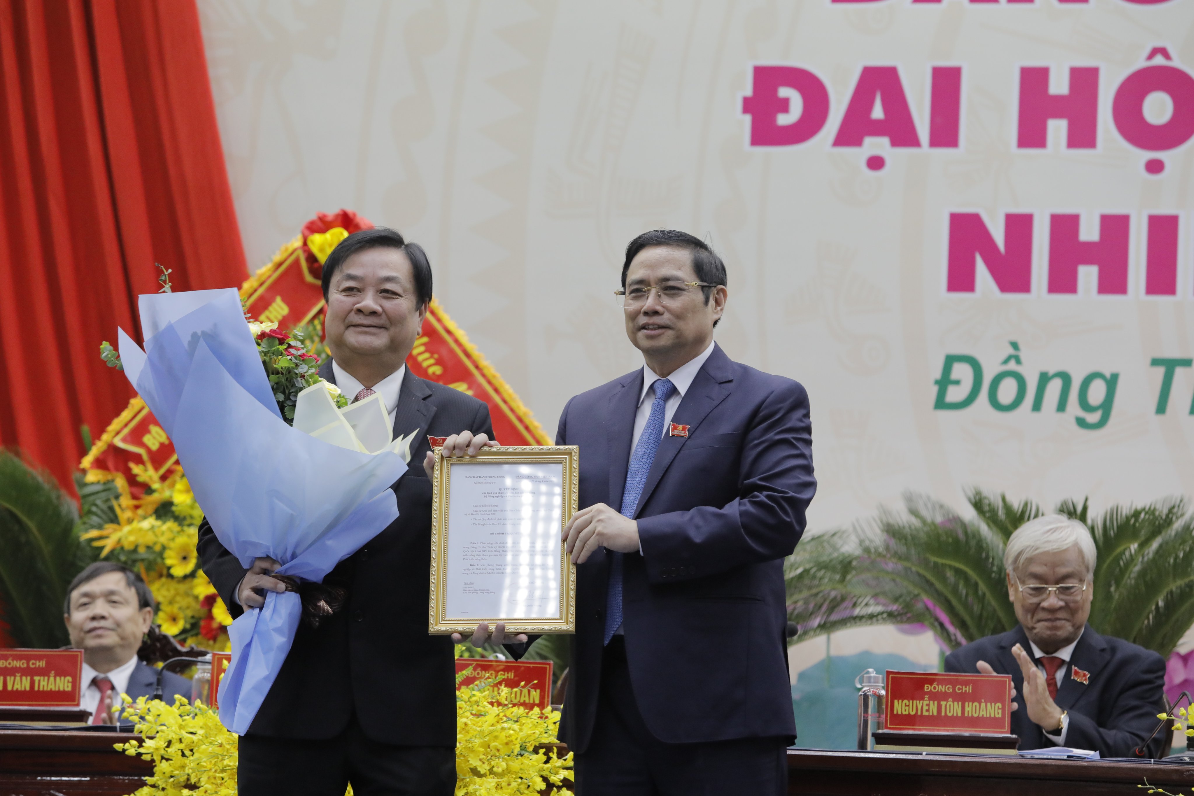 Đồng chí Phạm Minh Chính (bên phải) Trao Quyết định của Bộ Chính trị và tặng hoa cho đồng chí Lê Minh Hoan